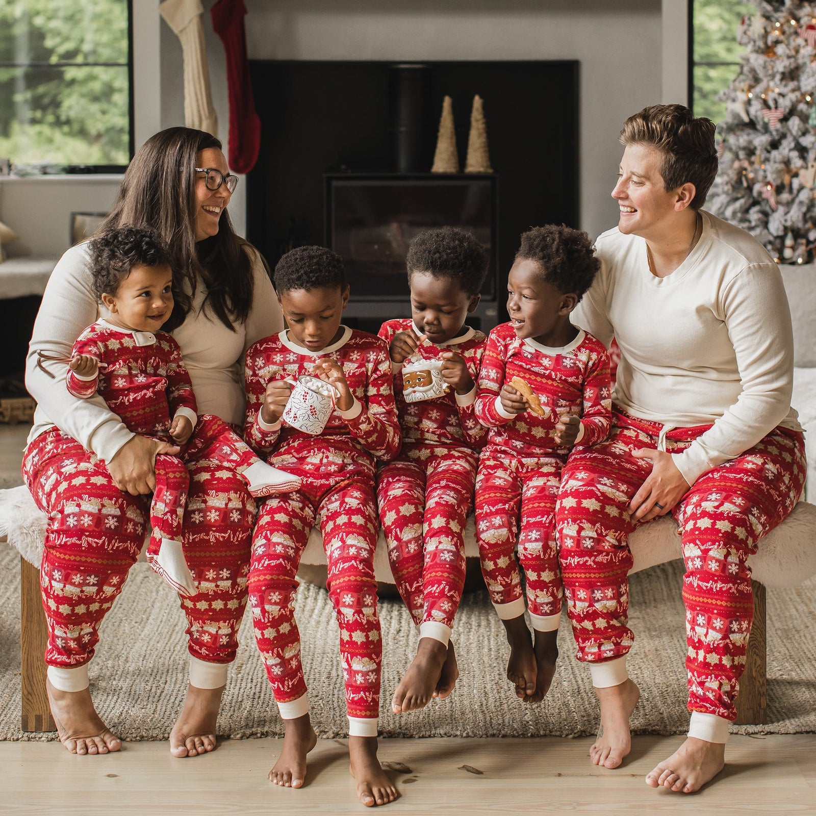 Full family sitting on bench wearing matching family pajamas with hot cocoa fair isle print from Burt's Bees Baby