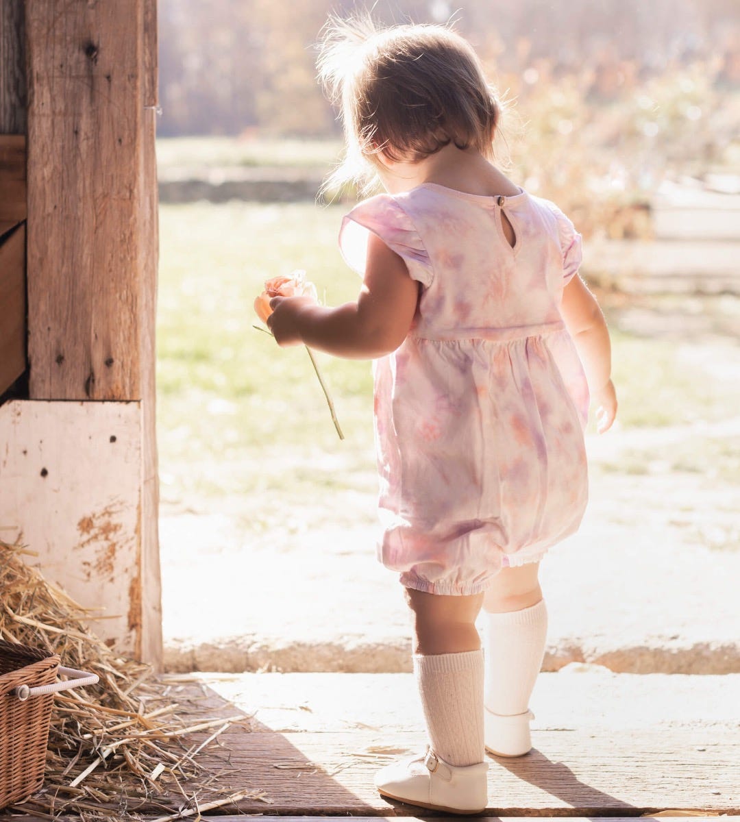 Infant girl walking out of barn wearing pink Cable Knit Knee High Socks Made and baby flats