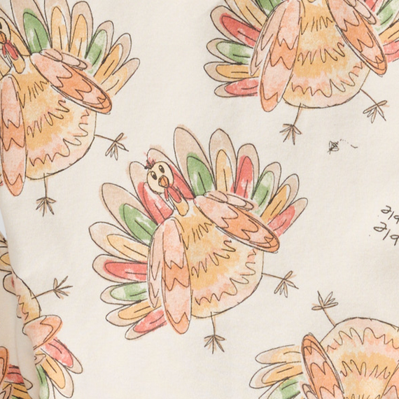 Close-up of cream fabric with colorful turkey and leaf pattern on a kids' sleeper