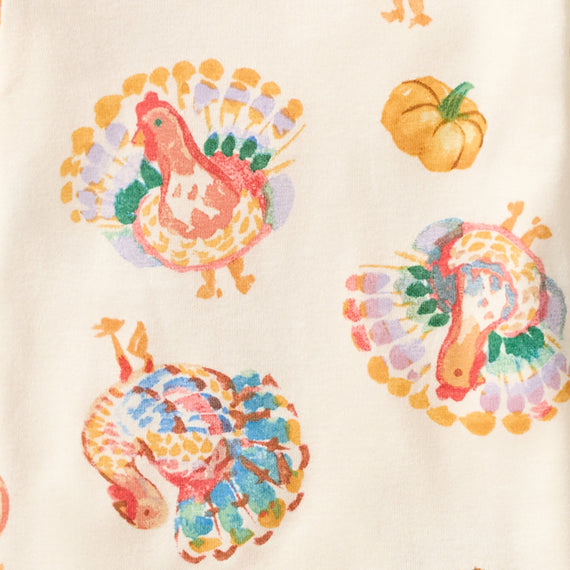 Cream pajama fabric with colorful turkey and pumpkin pattern close-up