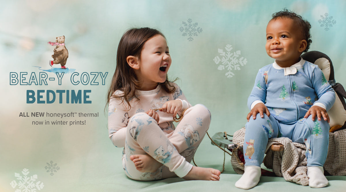 Two children sitting on the floor wearing matching winter pajamas, with a light blue background and snowflake graphics. Large text reads 'BEAR-Y COZY BEDTIME' and smaller text says 'ALL NEW honeysoft thermal now in winter prints!'.