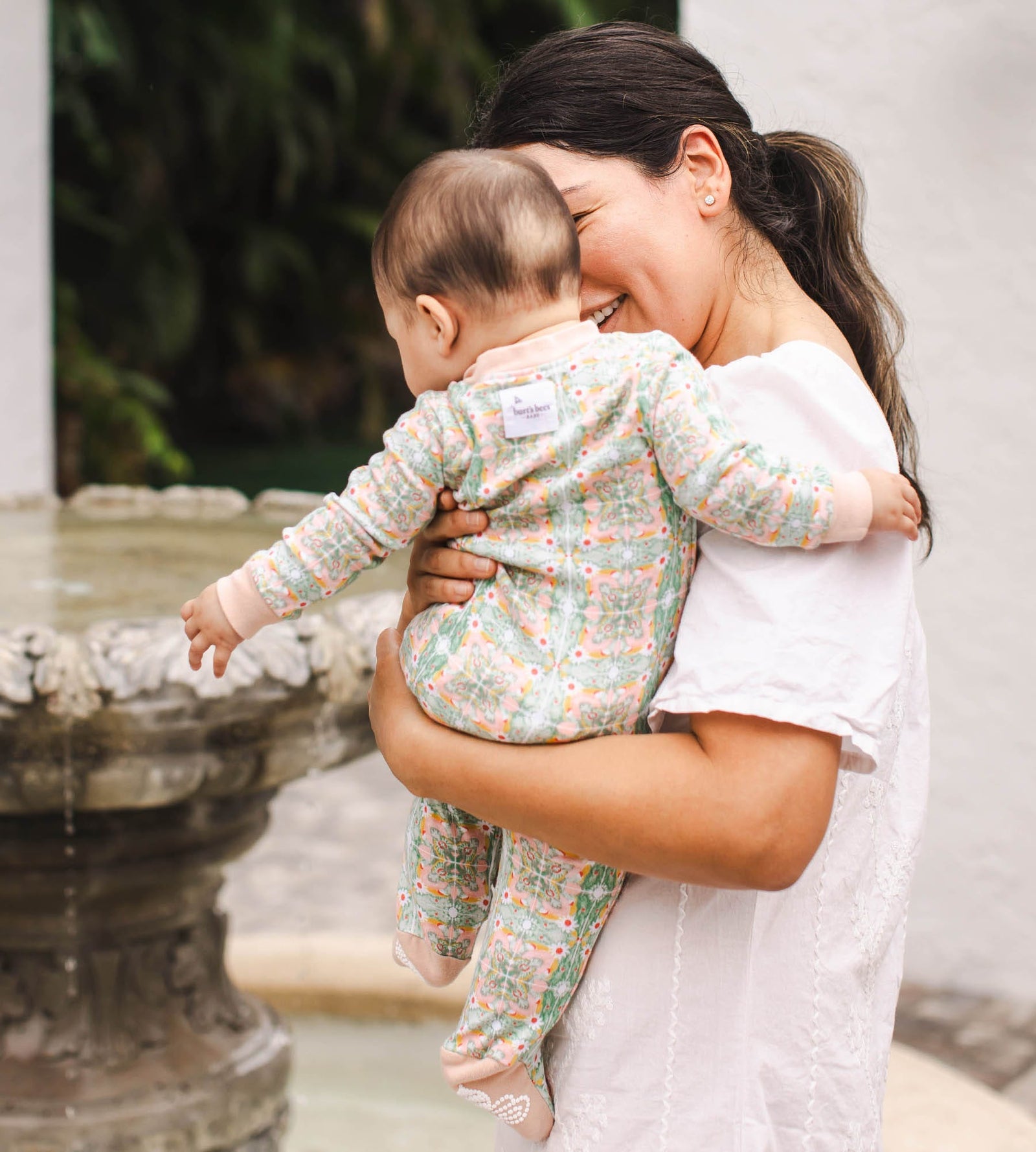 Back of baby being held by mom wearing floral tile print Burt's Bees Baby pajamas