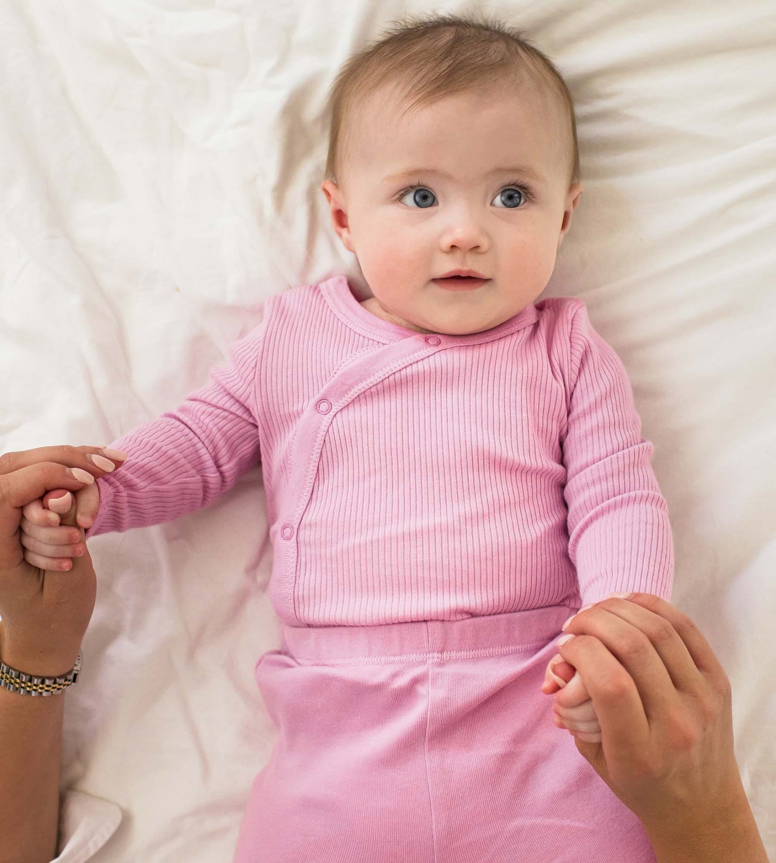 Baby laying on her back wearing Wrap Front Baby Girl Bodysuit Set holding moms hands
