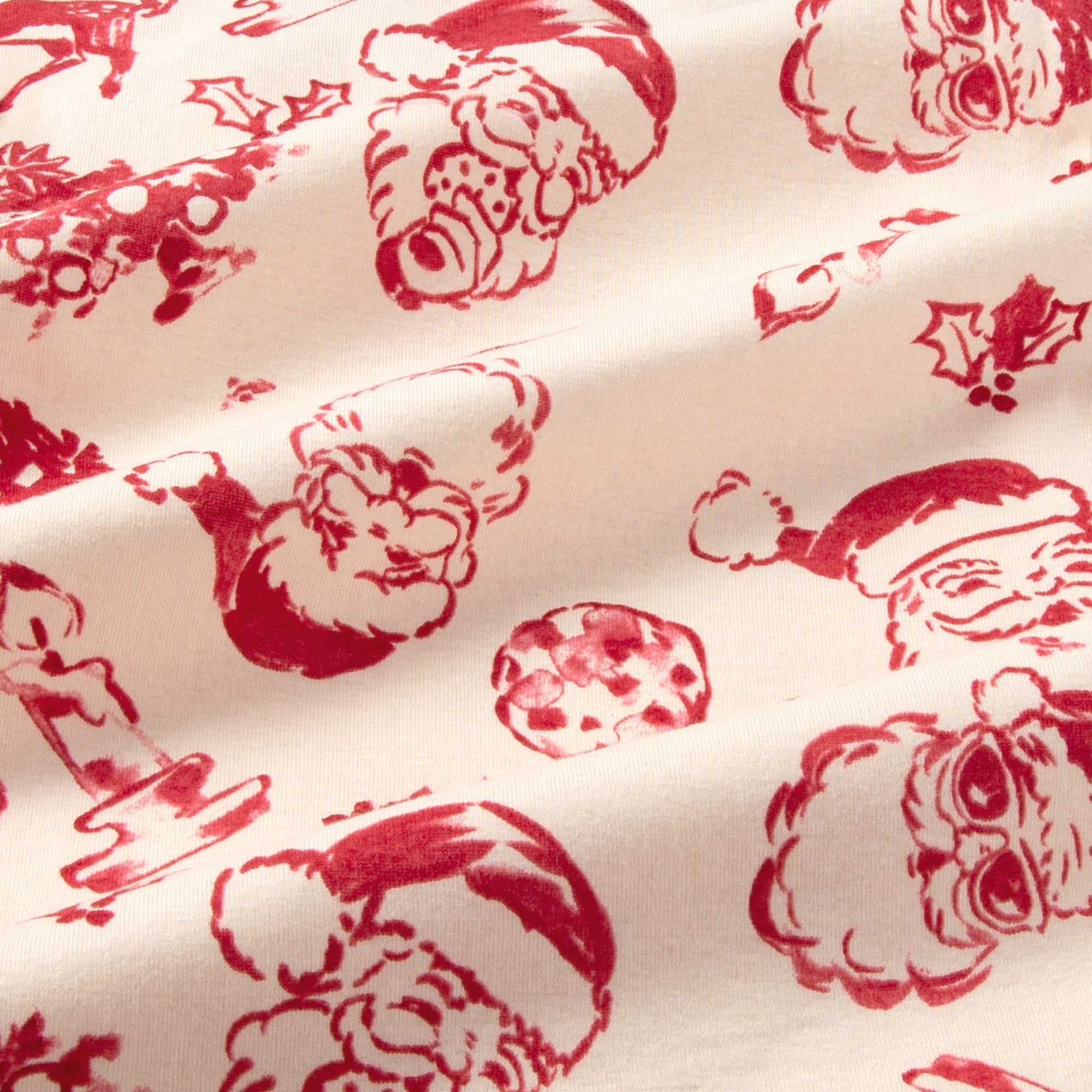 Cream organic cotton fabric close-up with red Christmas character prints