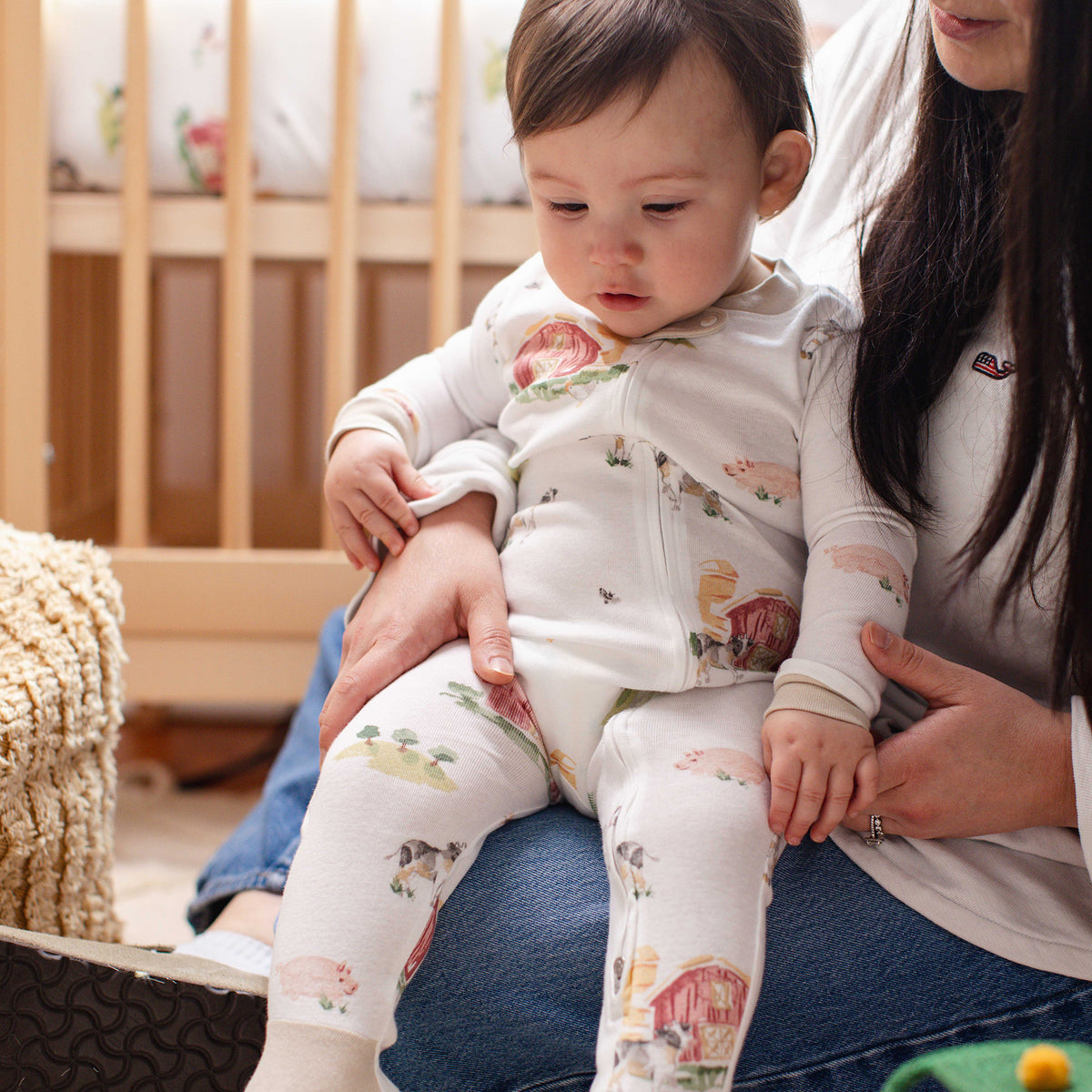 Off-white footed sleeper with colorful barnyard scenes, long sleeves, worn by baby - View 2