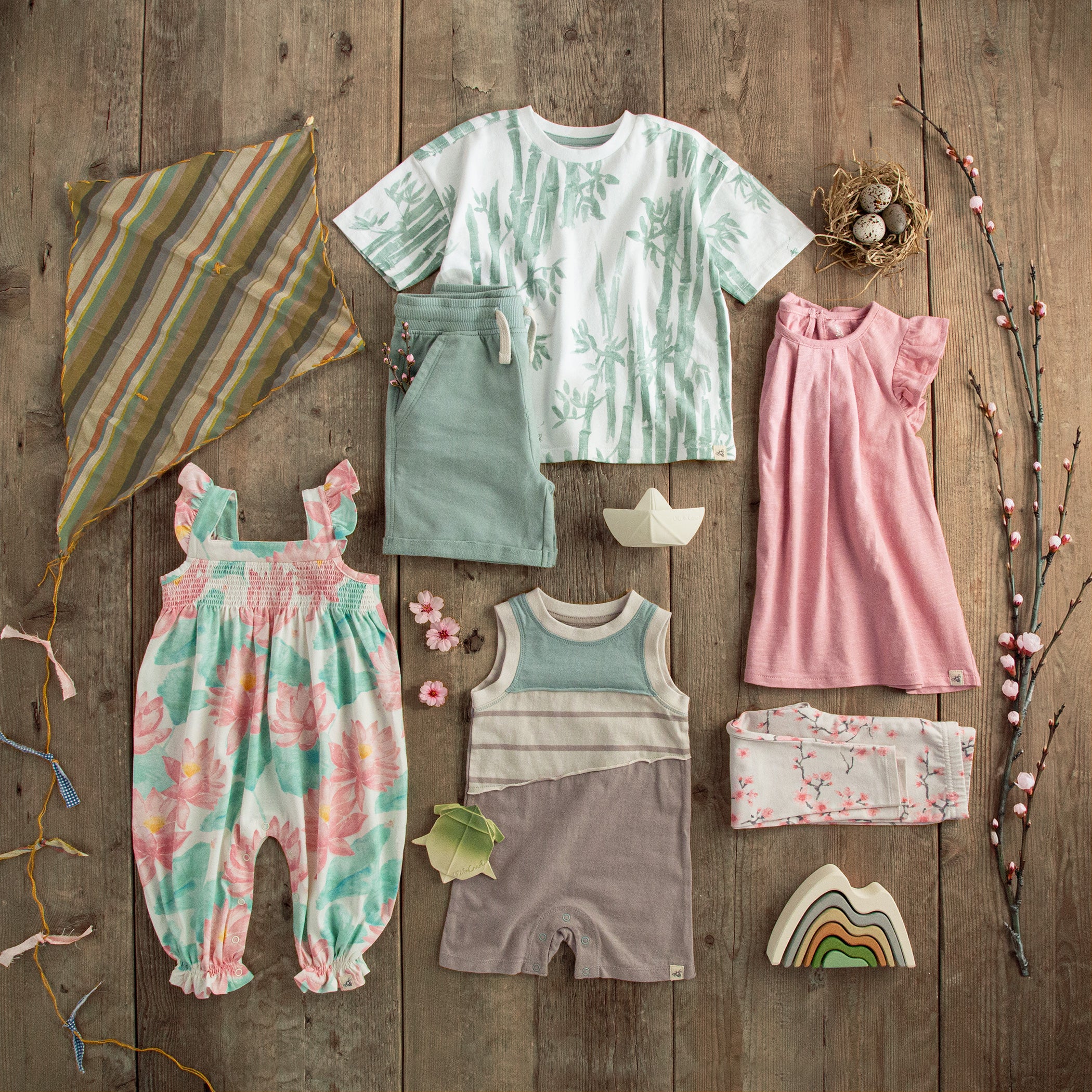 Collection of Burt's Bees Baby Spring collection children's clothing and accessories on a wooden surface